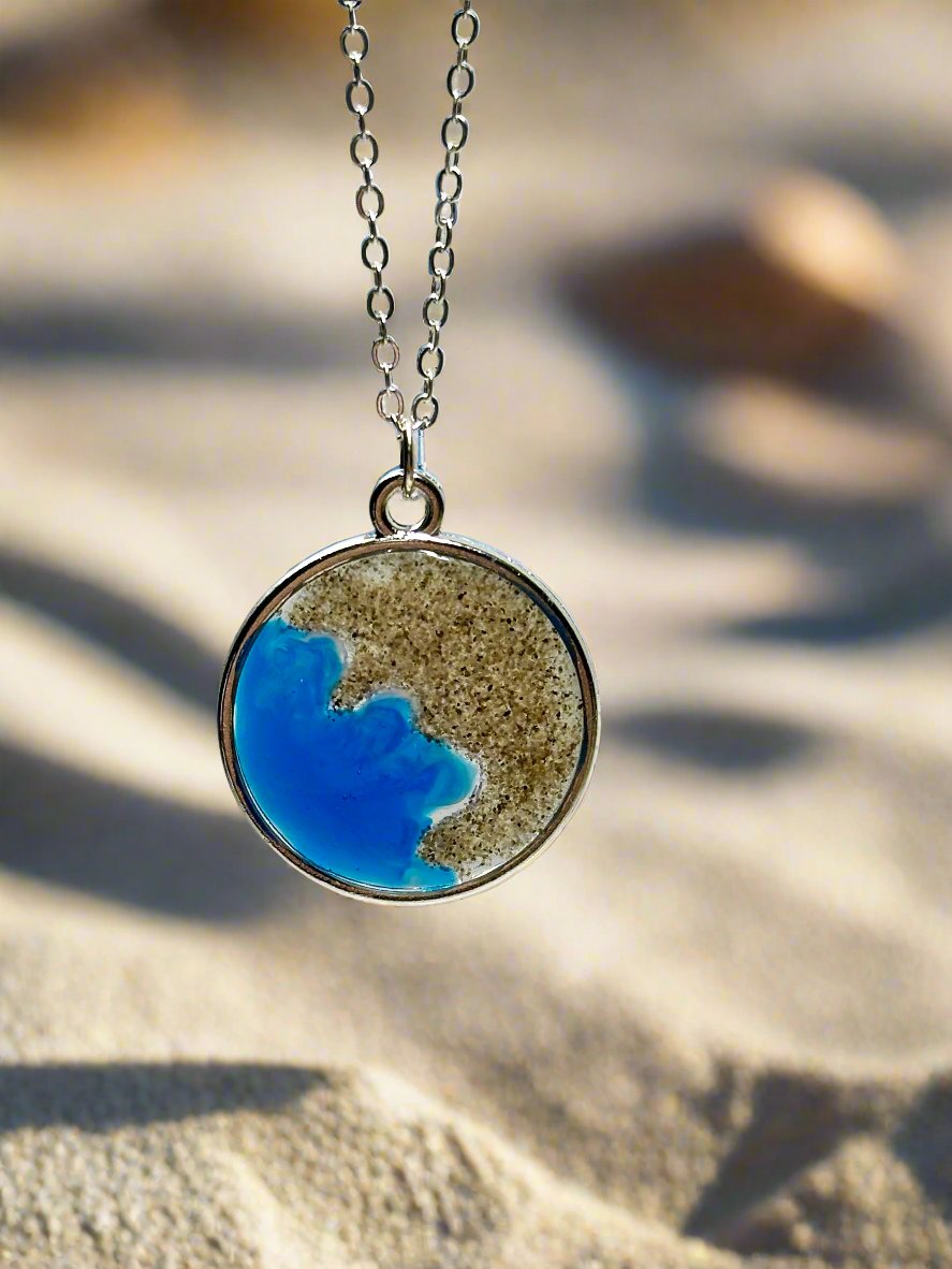 This is a picture of a pendant necklace made with real California sand representing the coast of Carmel.