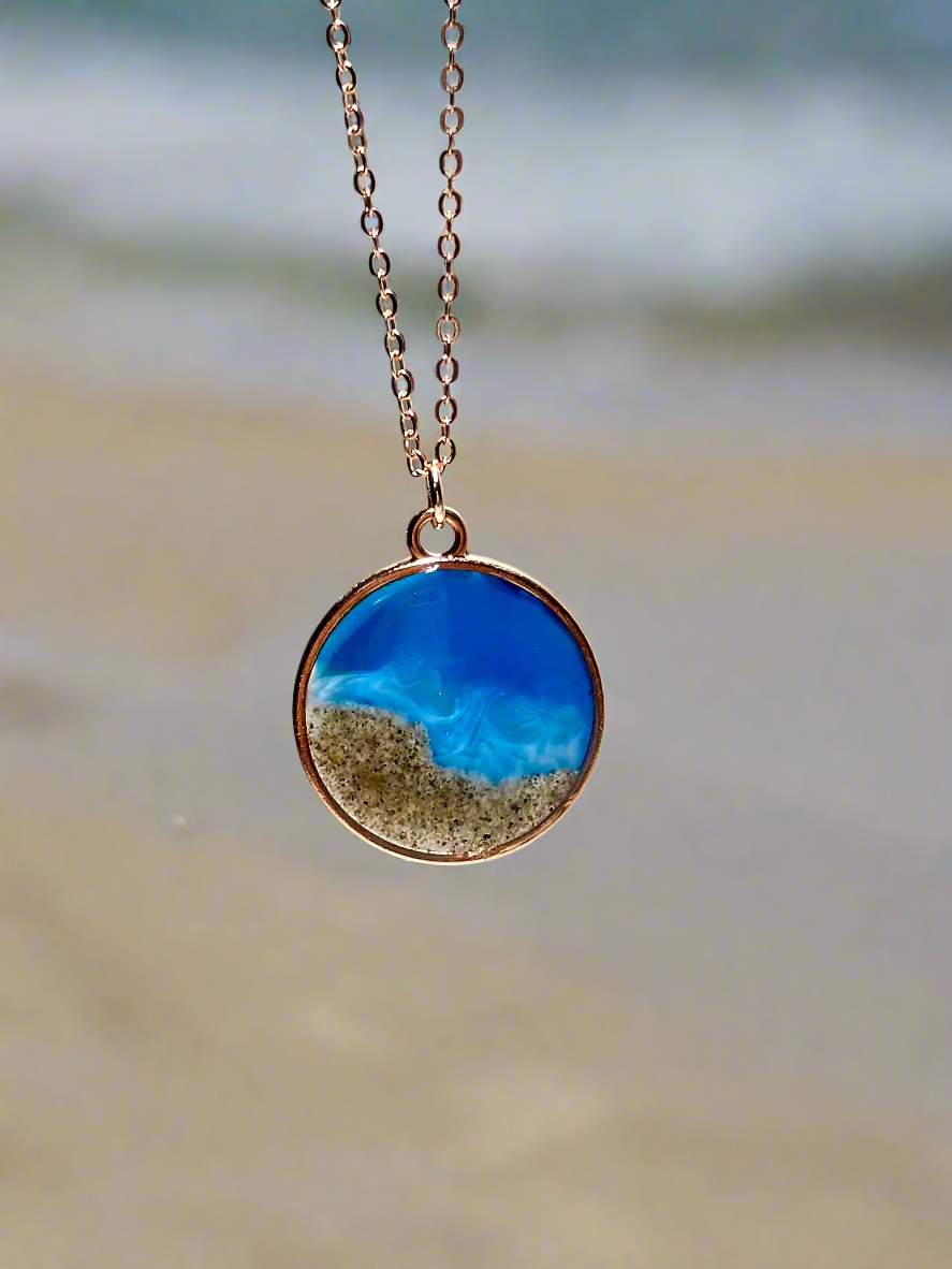 This is a picture of a round pendant necklace in rose gold representing the coast of monterey, ca.