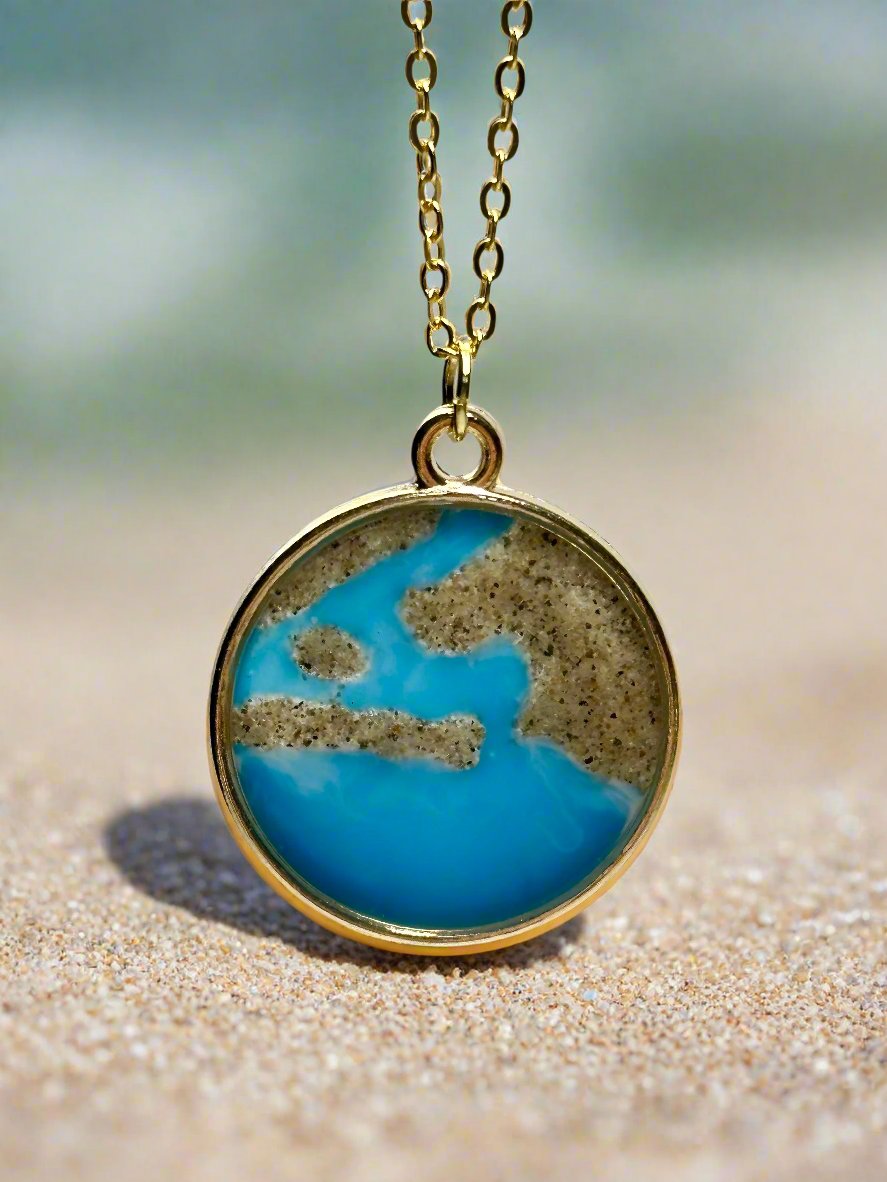 This is a photo of a pendant necklace made with real sand representing the coast of Newport Beach.