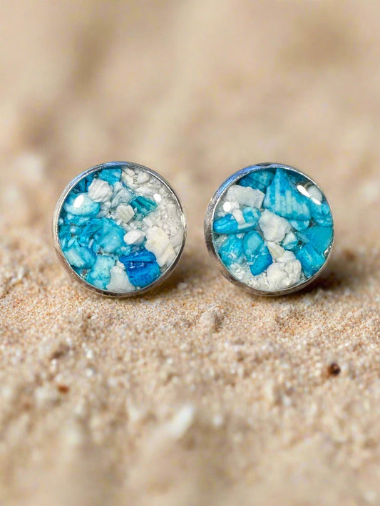 This is a photo of two small post earrings made with resin and blue and white shell pieces.