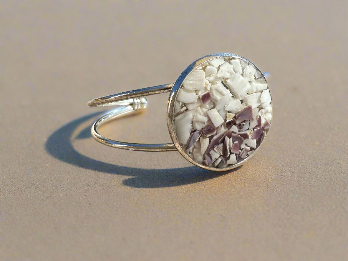 This is a profile view of the silver cuff bracelet with white and purple shells in center bezel.