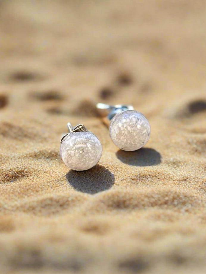 This is a picture of small round earrings made with crushed white seashell and resin.