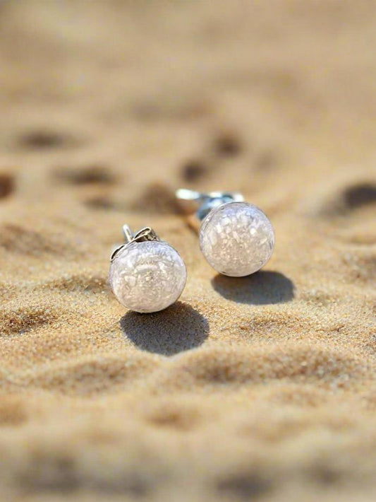 This is a picture of small round earrings made with crushed white seashell and resin.